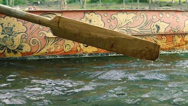 The boatman swims on a painted boat to the shore of a mountain river.