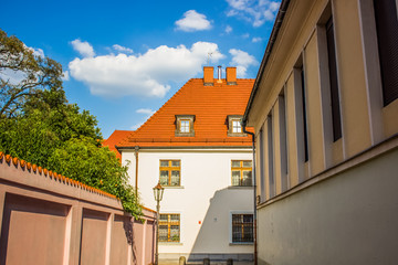 old city street symmetry concept with narrow alley way to small beautiful house with orange shingles roof in environment without people