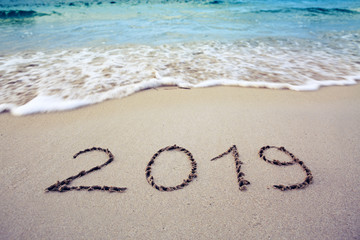 Year 2019 written at the caribbean sand beach with sea wave .