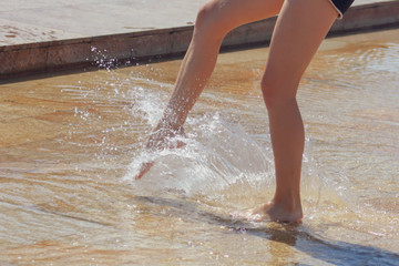 The legs of a girl in the water in a fountain