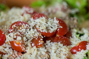 Macro shot of sunflower seeds, sesame, lin seeds on top of red cherry tomatoes next to parmesan cheese, lettuce, chicken. Freshly made caesar salads with dressing. Healthy vegetables, food in summer