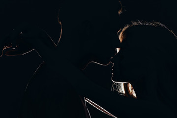 silhouettes of boyfriend kissing girlfriends nose in dark