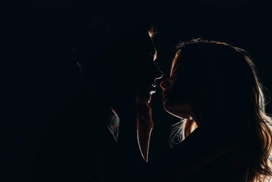 silhouettes of boyfriend and girlfriend going to kiss in dark