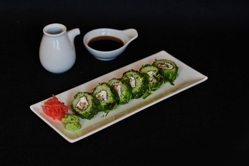 Sushi roll sushi with prawn, avocado, cream cheese, sesame. Japanese food. Healthy kale and avocado sushi roll with chopsticks.  Sushi on dark background. Set with, prawns, wasabi and ginger.