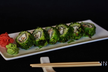 Food sushi background. Close up of sashimi sushi set with chopsticks and soy.  Japanese food restaurant,  sushi on dark background. Fresh made sushi set with salmon, prawns, wasabi and ginger.