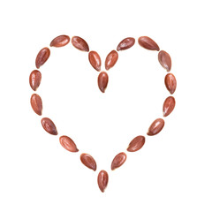 Close up of linseeds or flax seeds arranged in a heart shape isolated on white background