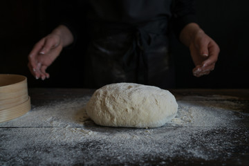 Food, cooking and baking concept. Yeast bread dough rising on wooden kitchen table at bakery. Woman preparing bread dough on wooden table in a bakery close up. Preparation of easter bread.