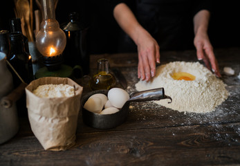 Food, cooking and baking concept. Making dough by female hands at bakery. Dough background. Preparation of the dough from fresh ingredients. On a rustic background. Ingredients for homemade baking.