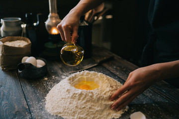 Food, cooking and baking concept. Making dough by female hands at bakery. Dough background. Preparation of the dough from fresh ingredients. On a rustic background. Ingredients for homemade baking.
