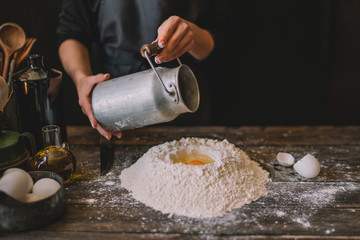 Steps of making cooking pie with ingridients. Mixing ingredients: flour, eggs, oil. See series. Step by step recipe. Cooking course or kitchen mess. Female hands make dough for biscuit or pie.