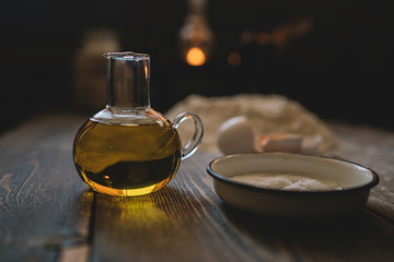 Food, cooking and baking concept. Baking bread in rustic kitchen. Dough recipe ingredients eggs, flour, milk, oil on dark vintage wooden table from above. Rural kitchen. Homemade food.