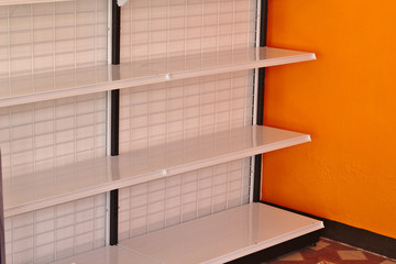 Empty shelves in the supermarket with orange walls.
