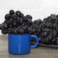 A branches of dark grapes in blue cup. The concept of winemaking. Rustic style.