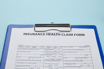 close-up view of insurance health claim form on clipboard isolated on blue