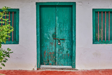 Fototapeta na wymiar Vintage green wooden door and window on worn wall.