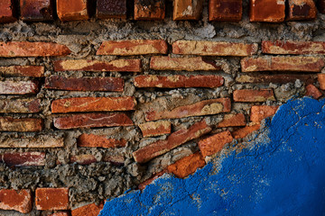 Abstract  brick wall  urban texture. Old red brick wall with shabby damaged plaster. Part of the wall is plastered and painted in blue. Background of old vintage dirty brick wall with peeling plaster.