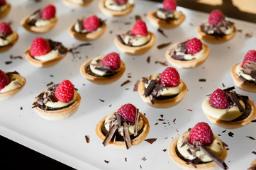 Raspberry and chocolate pastry bites with chocolate shavings.