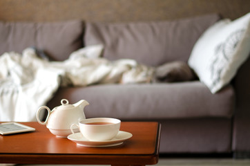 Cozy home interior with teapot, cup of tea and eBook