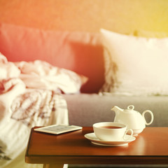 Fototapeta na wymiar Cozy home interior with teapot, cup of tea and eBook
