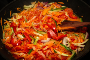 The process of cooking vegetable stew. Frying pan, wooden spatula. A colorful photo. Bright.