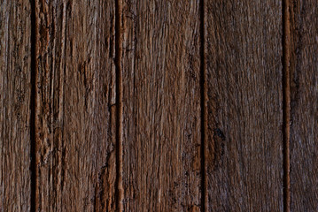 Boards together with knots and traces of bark beetle. Old weathered rotten knotted coarse brown grunge wooden fence. Texture and background nature old wood..