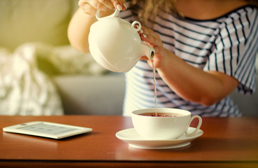 Cozy home interior with teapot, cup of tea and eBook