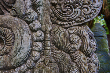 Detail of relief  wall with stone carving in Bali,Indonesia. Temple with traditional stone carving indonesia. Relief sculpture on the wall of a Buddhist temple. Ancient stone carving covered with moss