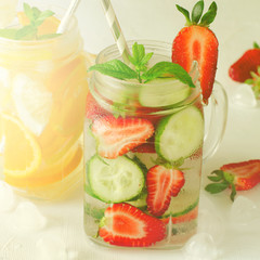 Summer refreshing iced drinks with orange, lemon, cucumber and strawberry on white background