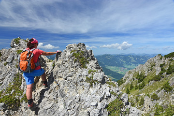 Female hiker climbing at an exposed ridge close to the village Oberstdorf in the Allgau Alps,...