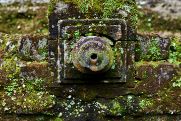 Close-up covered moss ancient stone carving in the Balinese temple .