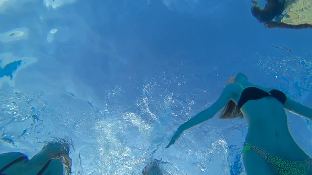 summer leisure, girls swims under transparent blue water in swimming pool