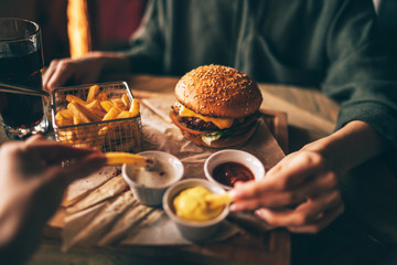 Group of friends eating at fast food. Friends are eating burgers while spending time together in...