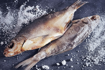 Two dry salted fishes on a gray  background.