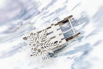 Abstract blurred festive Christmas background. Wooden decoration, snowflake on little wooden sled