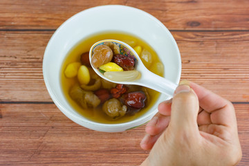 boiled ginkgo longan juice with dry jujube and  nipa palm fruit , hand hold spoon