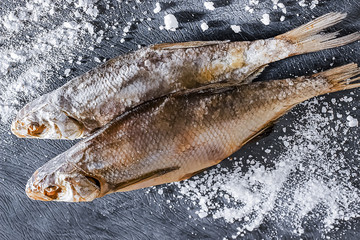 Two dry salted fishes on a gray  background.