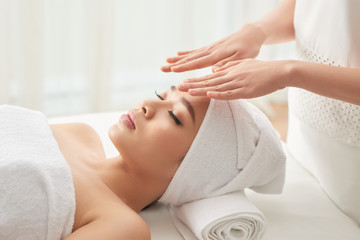 Anonymous woman holding hands over face of attractive female client during spa session in salon