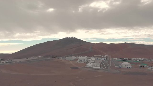 Aerial view of Very Large Telescope VLT in Atacama desert Chile. Drone rising up during cloudy day. Science and space research facilities foreground and telescopes background at the summit.