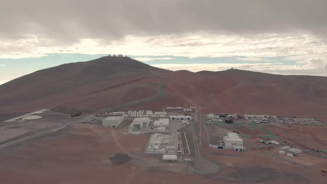 Aerial view of Very Large Telescope VLT in Atacama desert Chile. Drone rising up during cloudy day. Science and space research facilities foreground and telescopes background at the summit.