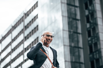 Businessman talking over mobile phone walking outdoors