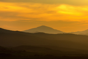 Rolling hills in silhouette in dawn light in Tuscany