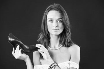 cute stylish brunette girl holding a shoe on a black background