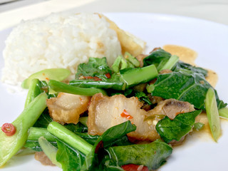 Stir fry Kai Land and crispy pork, stir fried rice with rice in white dish on white background. Thai style food.