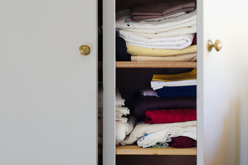 Piles of clothes, towels, sheets in an open wardrobe