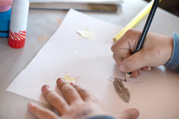 Creative workshop for kids. Little boy with dirty hands drawing on white paper at school. Concept of art, crafts and kids having fun. Messy table  
