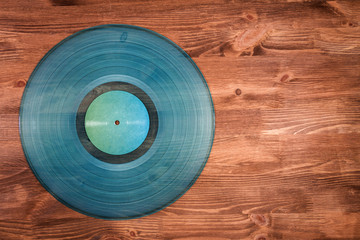 Cyan vinyl record on brown wooden background