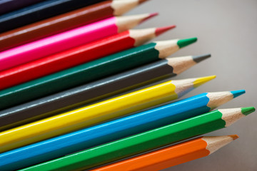 Pile of sharp coloured drawing pencils on table. Rainbow colors  red, yellow, blue, green, purple. Concept of art, crafts and kids having fun