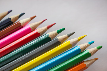Pile of sharp coloured drawing pencils on table. Rainbow colors  red, yellow, blue, green, purple. Concept of art, crafts and kids having fun
