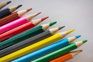 Pile of sharp coloured drawing pencils on table. Rainbow colors  red, yellow, blue, green, purple. Concept of art, crafts and kids having fun