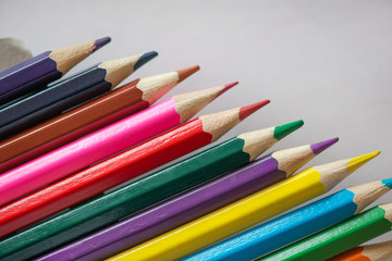 Pile of sharp coloured drawing pencils on table. Rainbow colors  red, yellow, blue, green, purple. Concept of art, crafts and kids having fun
